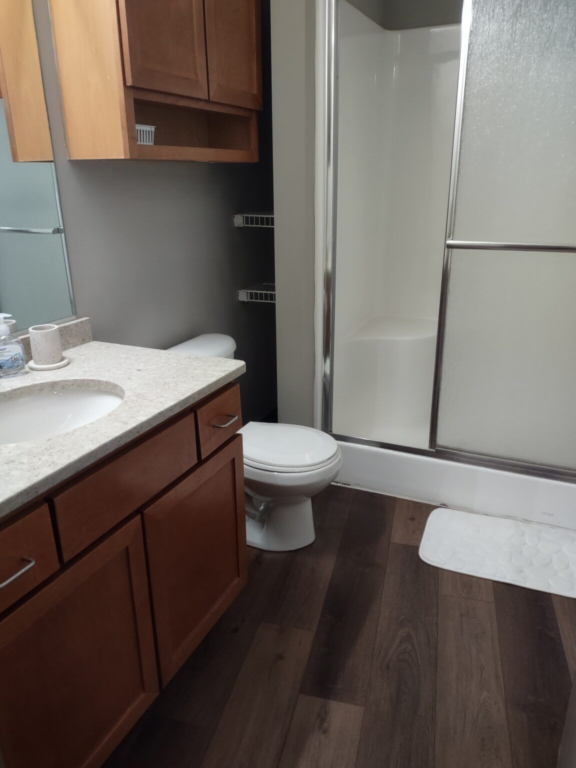 Clean bathroom with a wood vanity, white sink and glass shower door