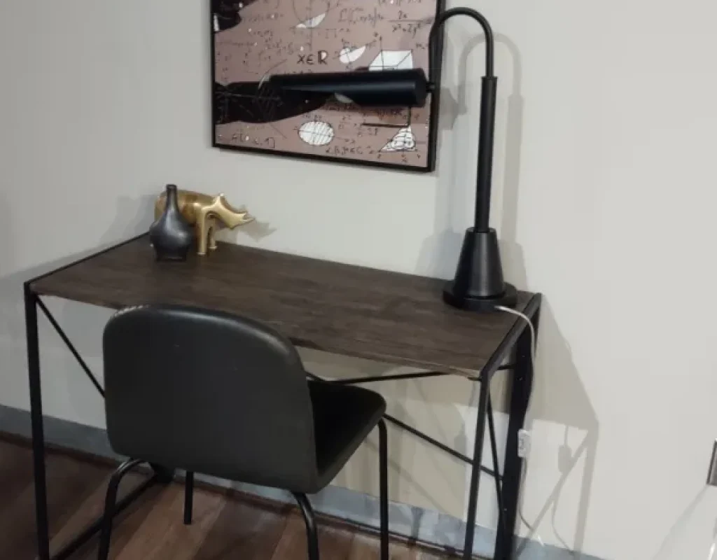 Clean wall, baseboard, and wood-look floor beside a small desk and chair after a move out cleaning in Bennington, NE.
