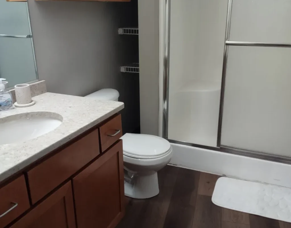 Clean bathroom vanity, sink, toilet, and glass shower door prepared during a move out cleaning in Bennington, NE.
