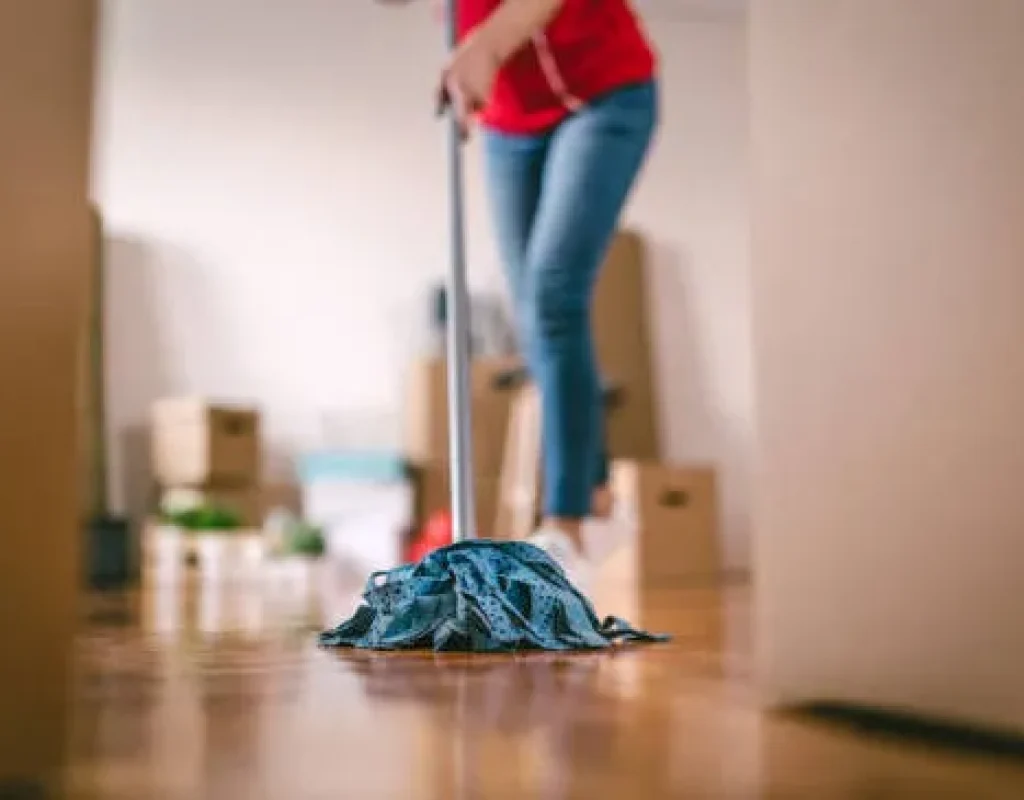 Cleaner removing dust from floor edges after furniture removal in Gretna, NE.