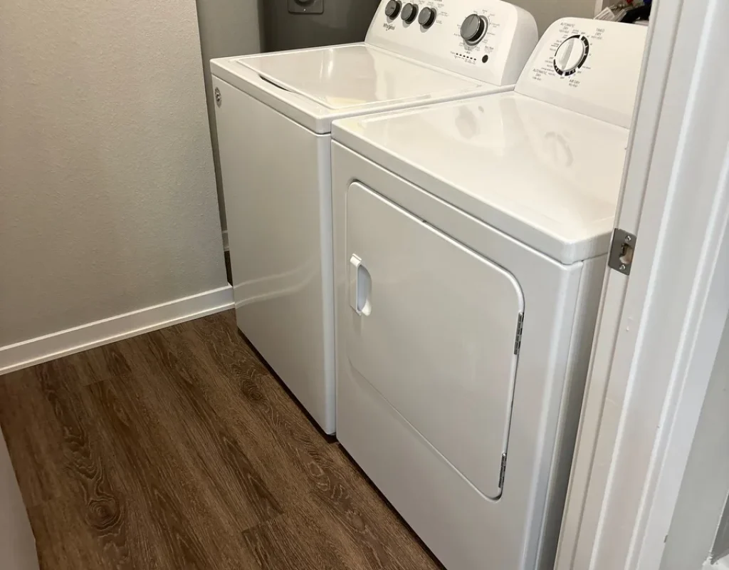 Laundry room with a white washer and dryer and a clean wood-look floor, part of a whole-home move out cleaning in Millard, NE.